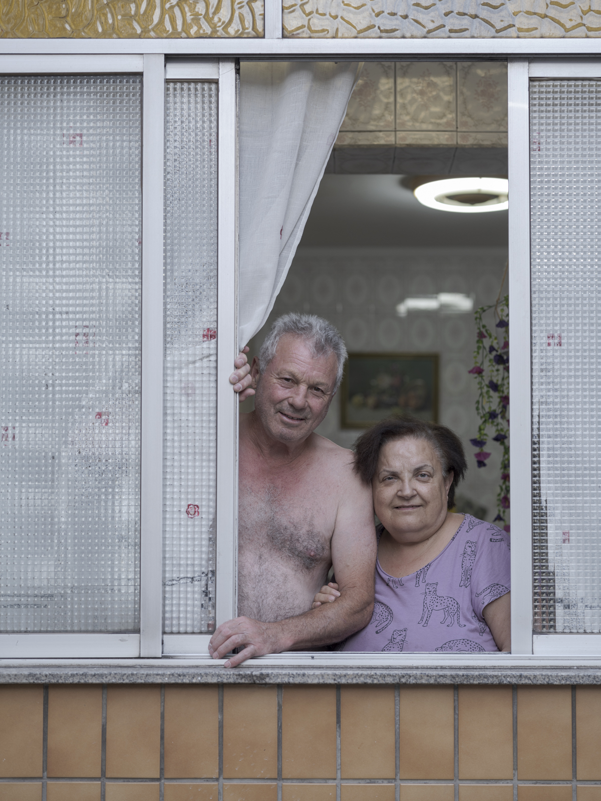 Retrato de pareja de mediana edad apoyada sobre la ventana